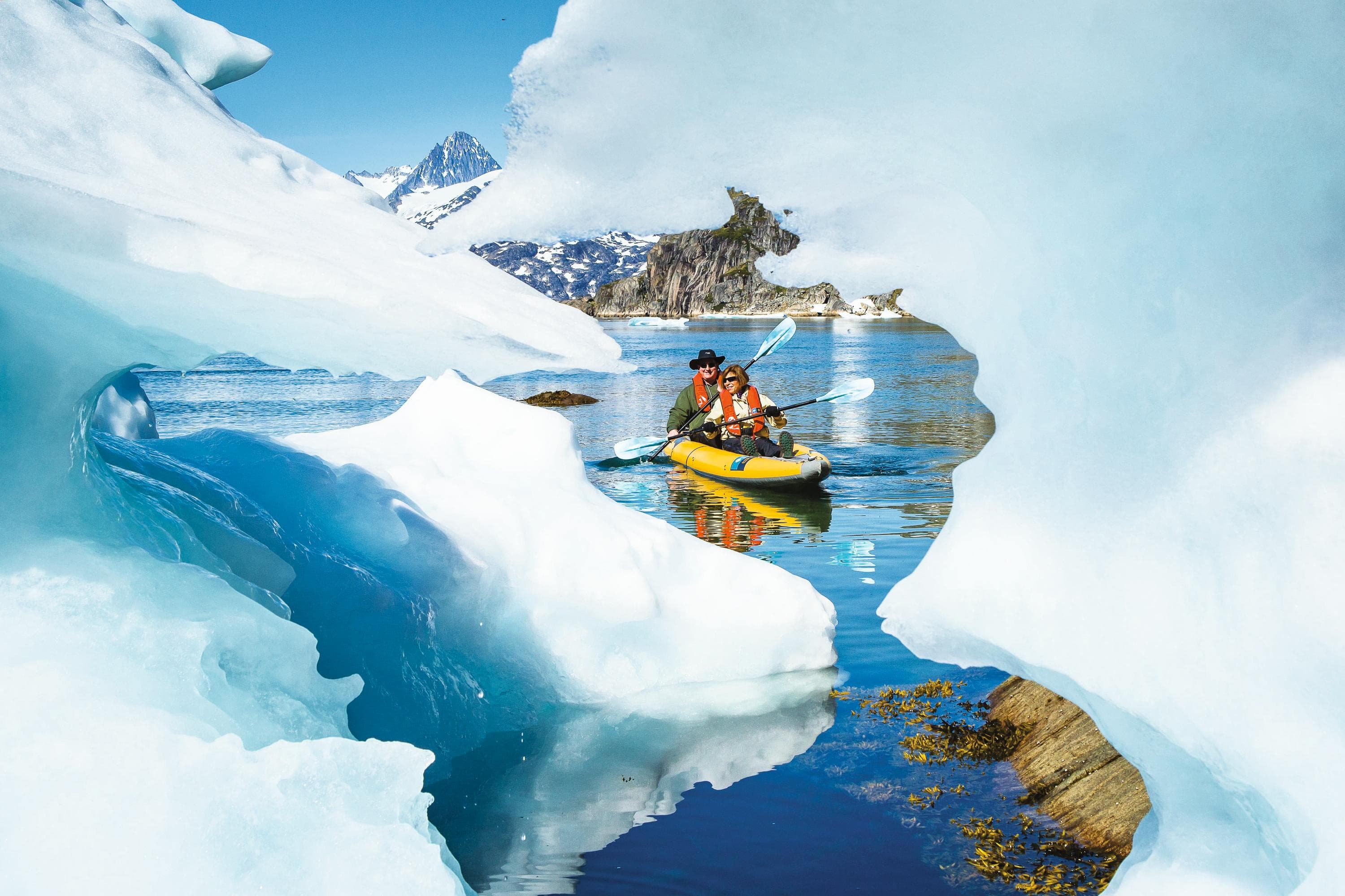 Guests kayaking around Icebergs from the ship National Geographic Explorer in Skjoldungen Island, Southeastern Greenland