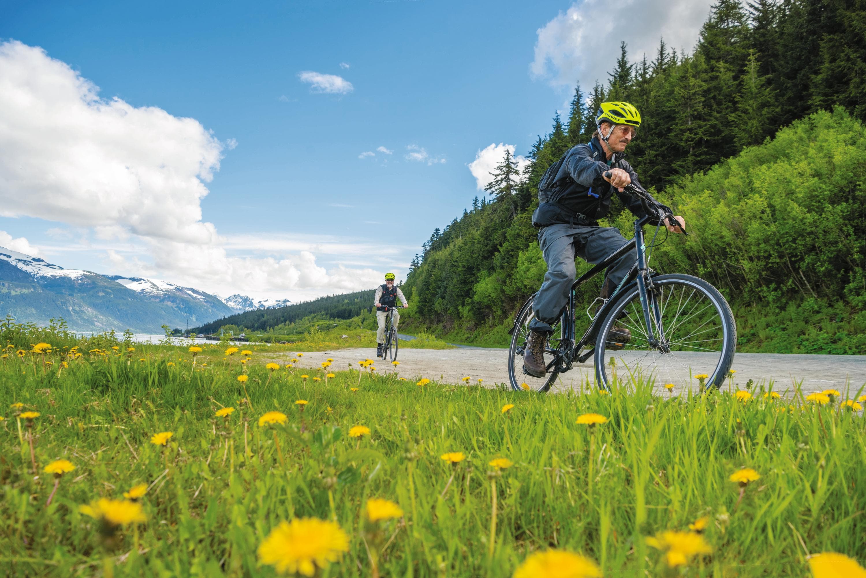 Guests enjoy a scenic bicycle ride along a glacial fjord to salmon spawning grounds overlooking an emerald lake in Haines, Alaska, USA