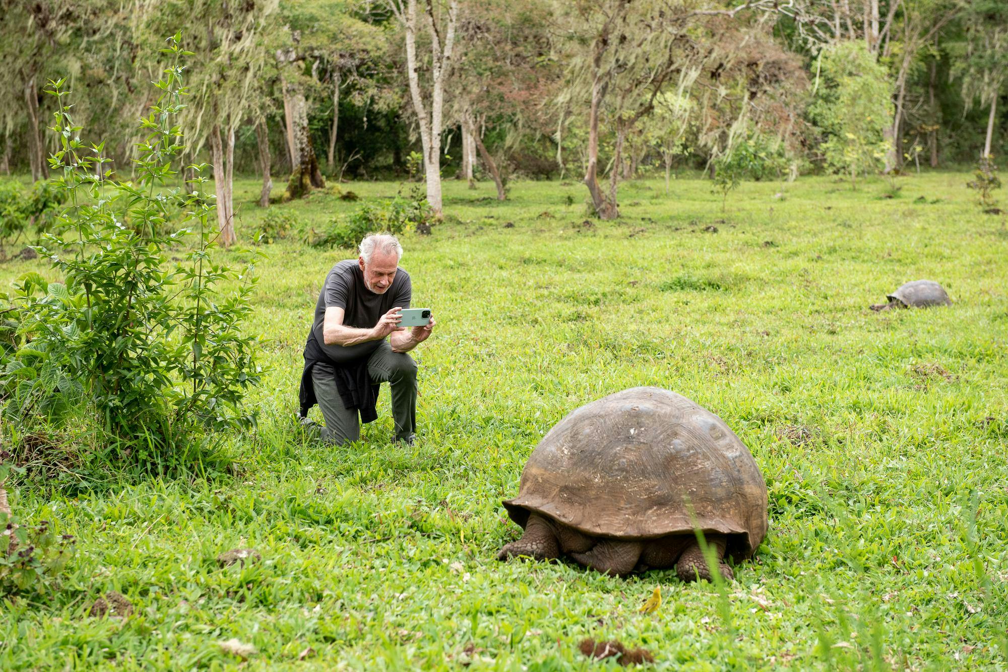 Sven Lindblad photographing a tortoise in the highlands of Santa Cruz island, Galapagos.