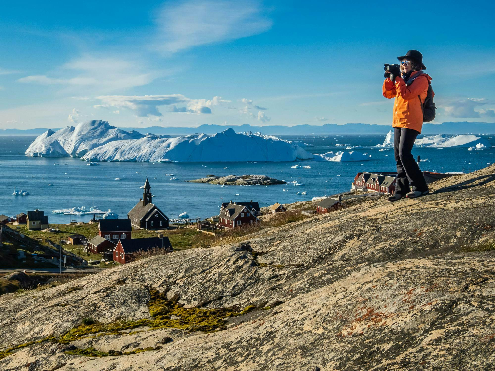 A guest photographs the view at the scenic viewpoint above the historic Zion Church, Ilulissat, Greenland