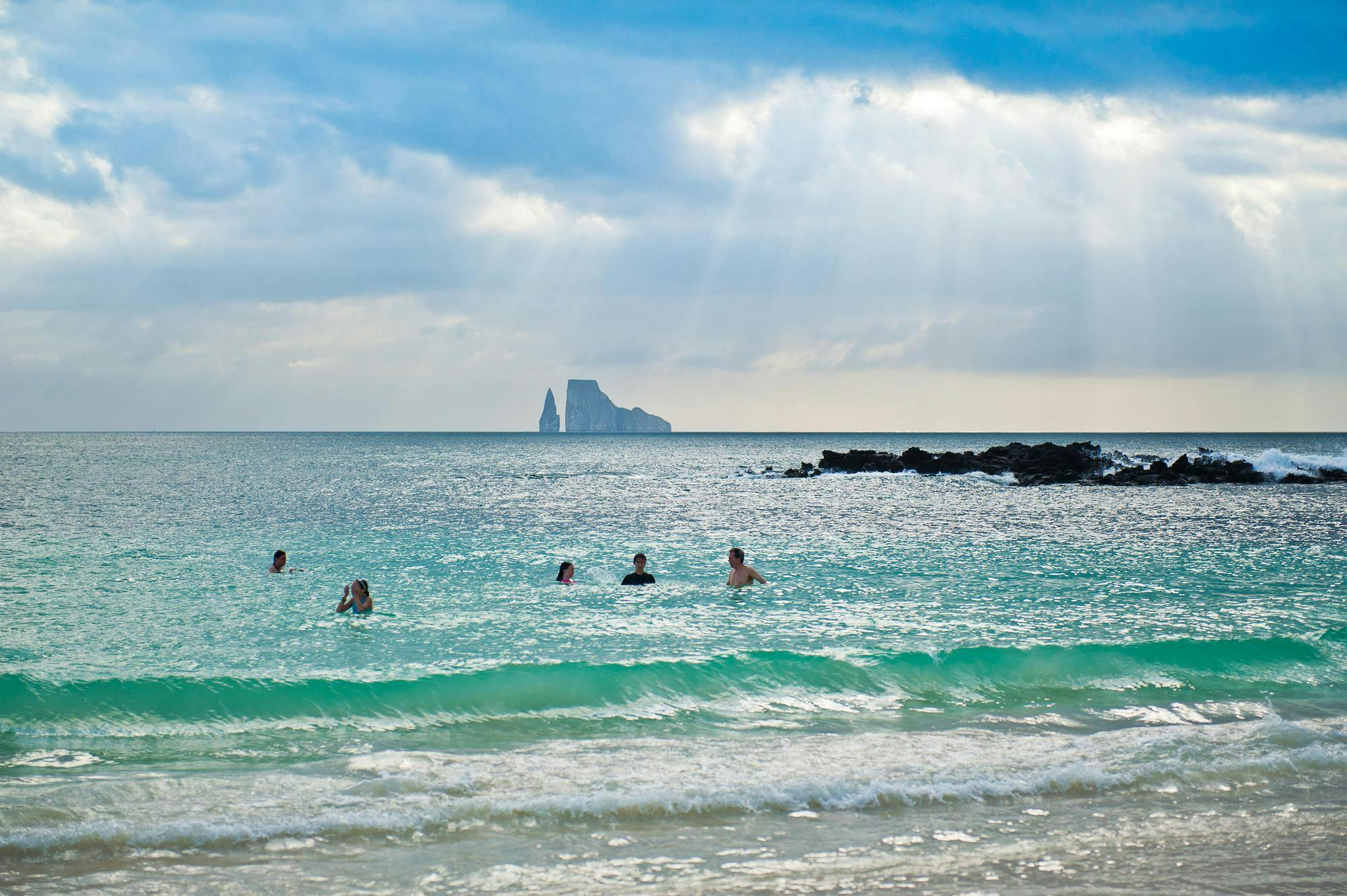 Guests swimming with view of Kicker Rock in the distance.