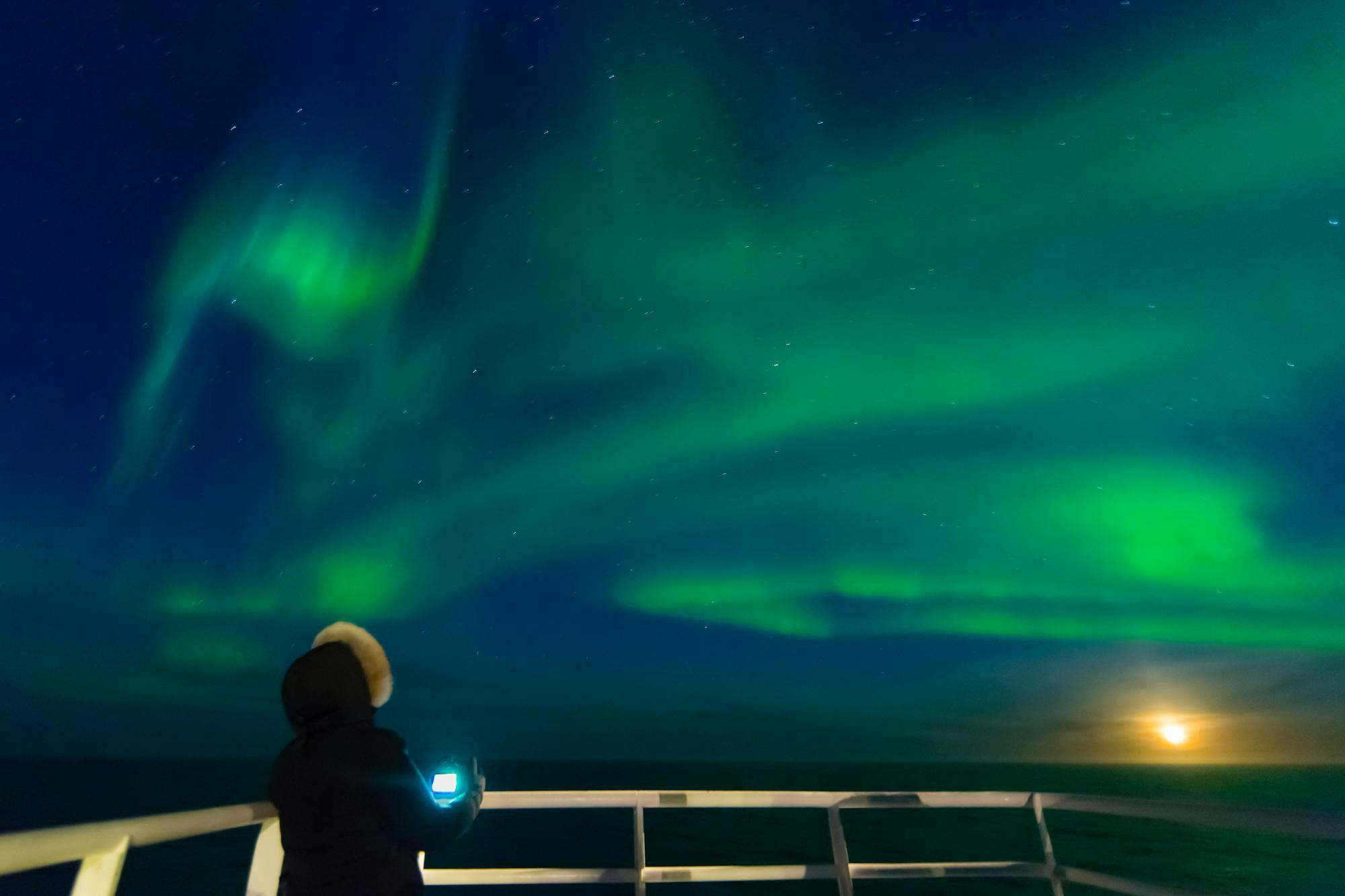 A guest photographing the, Northern Lights on the ship National Geographic Explorer, Foxe Basin, Nunavut, Canada