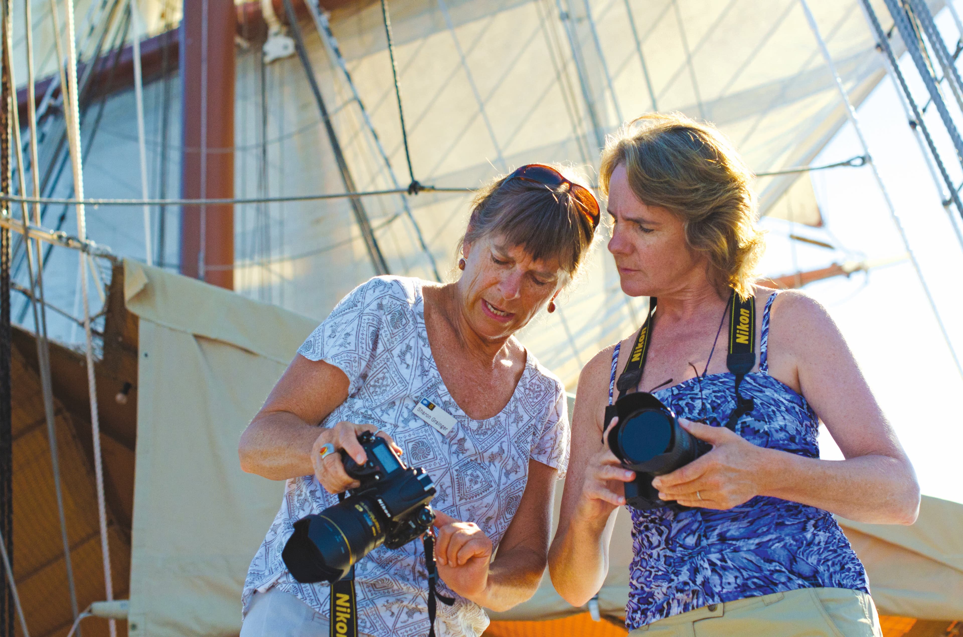 A guest receives photography tips from a certified photo instructor on the ship Sea Cloud