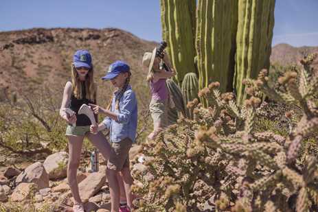 Two kids hold animal bones while a mom takes a photo of a cactus, San Esteban Island, Baja California, Mexico