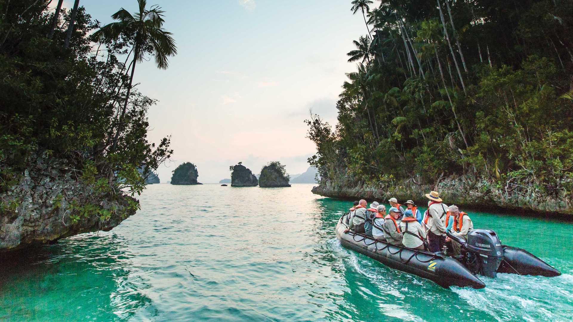 A Zodiac boat cruises through the emerald green waters of Indonesia