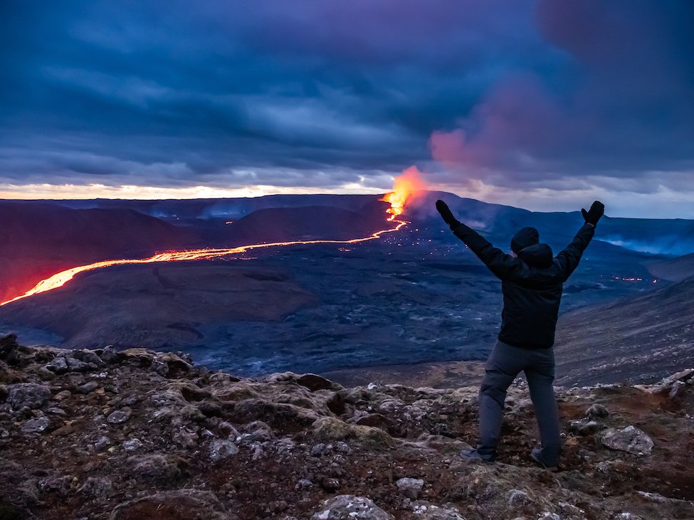 A man throws his hands up in celebration as Iceland's volcano erupts in the distance
