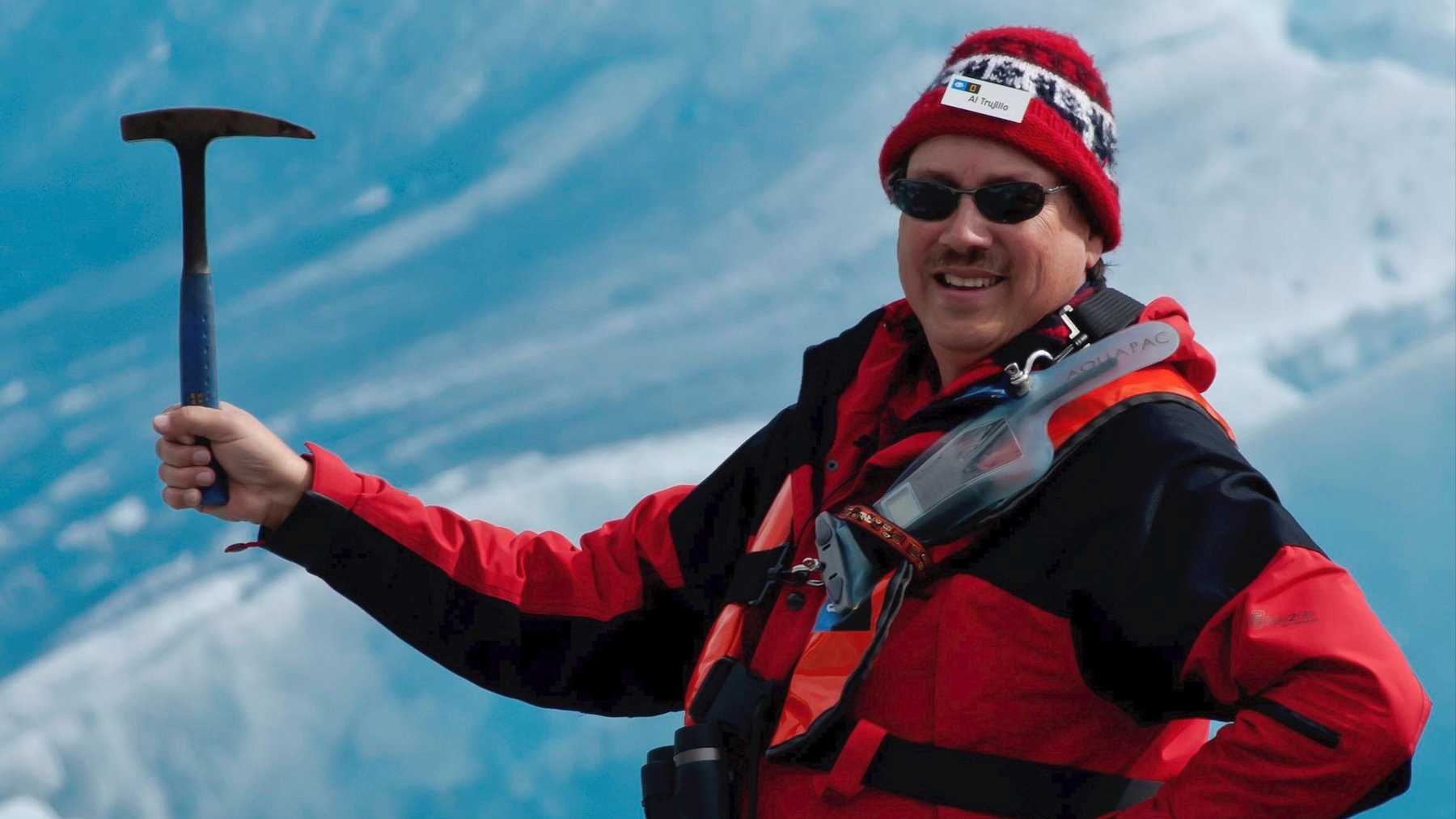 Man holding a pickaxe in front of an Alaskan glacier