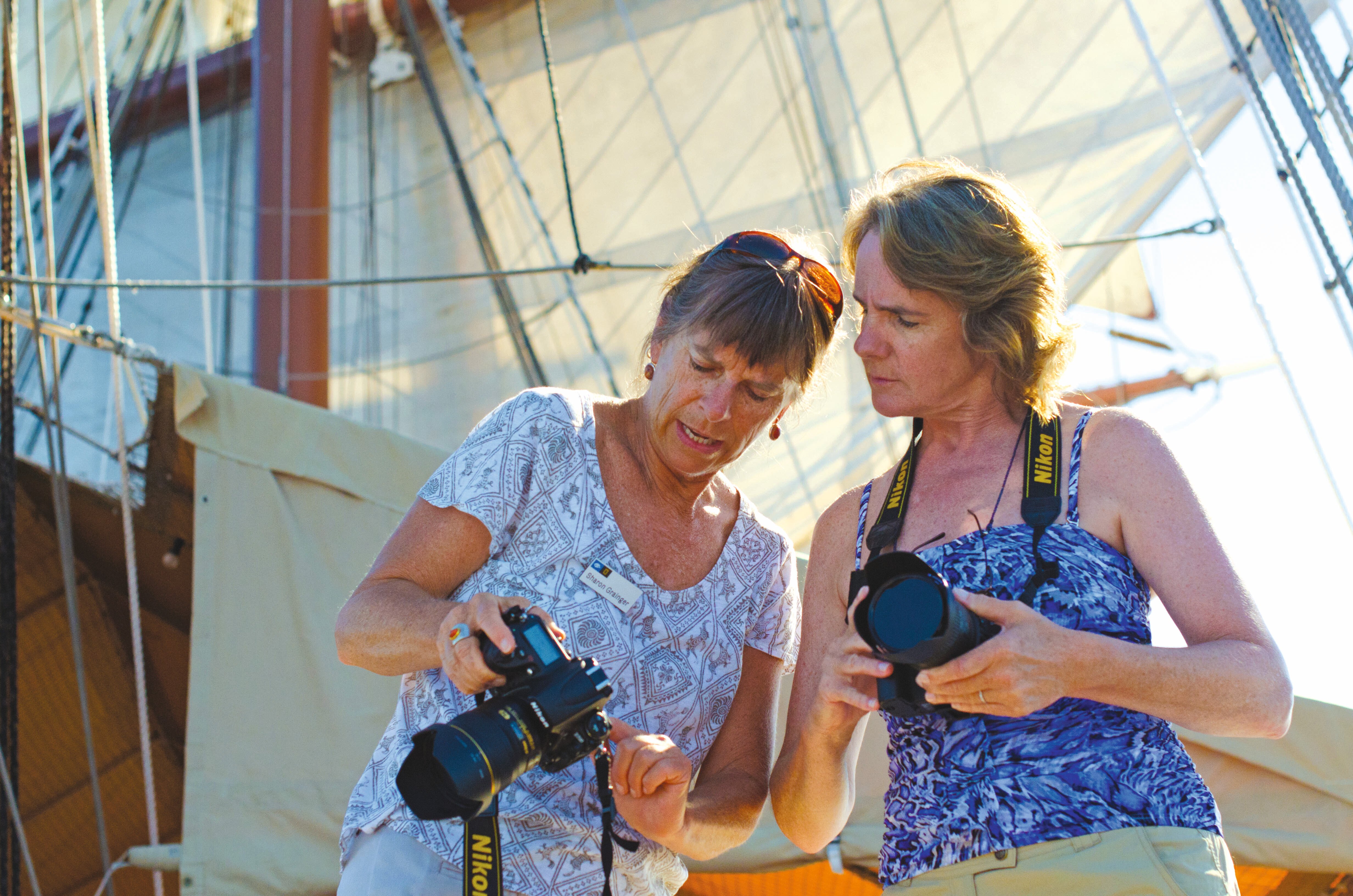 A guest receives photography tips from a certified photo instructor on the ship Sea Cloud