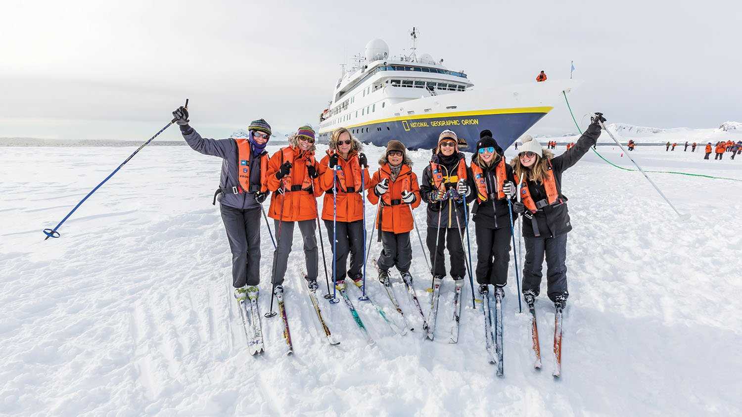 A group of guests cross country skiing pose in front the National Geographic Orion in Antarctica