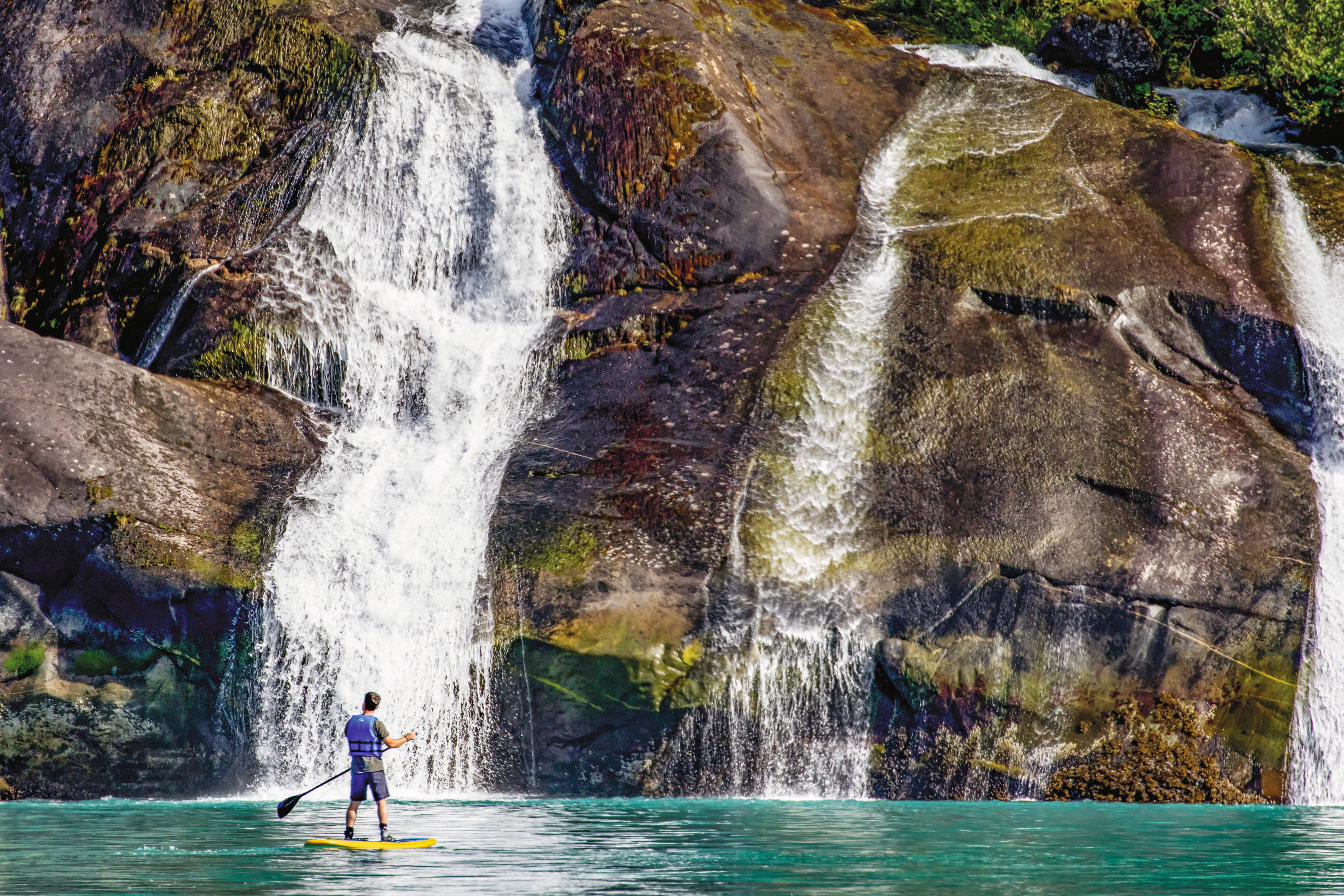 A guest explores by standup paddle board in Tracy Arm, Alaska.