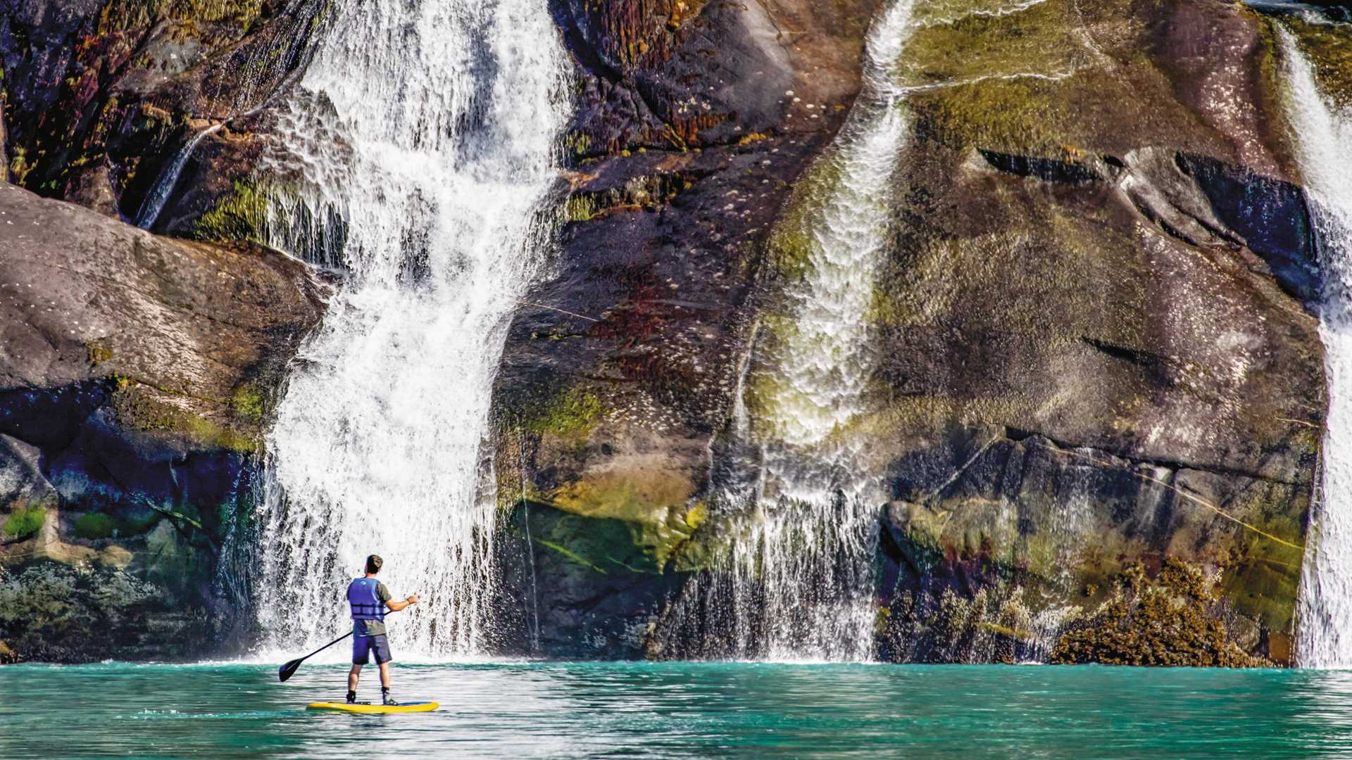 A guest explores by standup paddle board in Tracy Arm, Alaska.