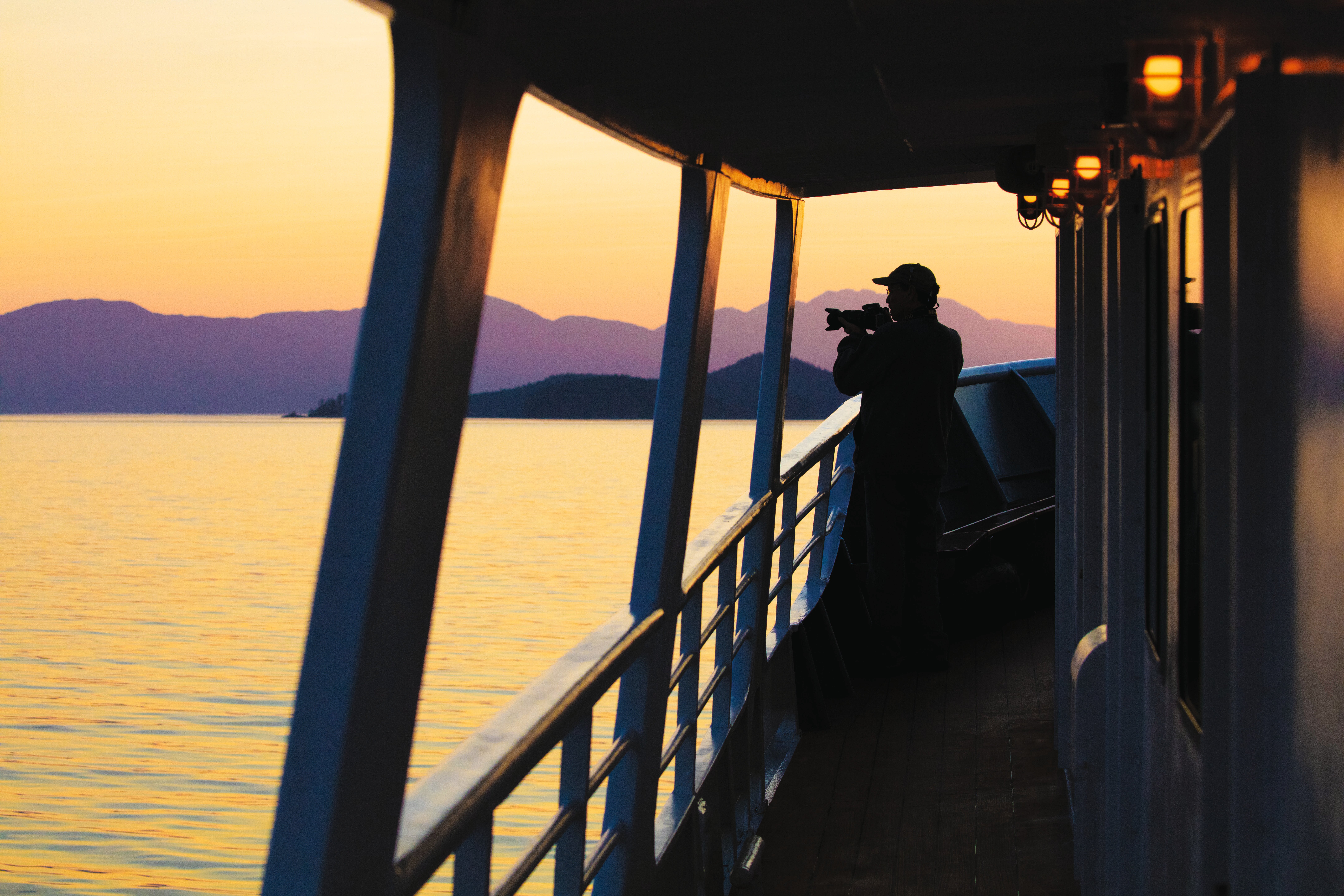 A man photographs the Alaskan landscape at sunset.