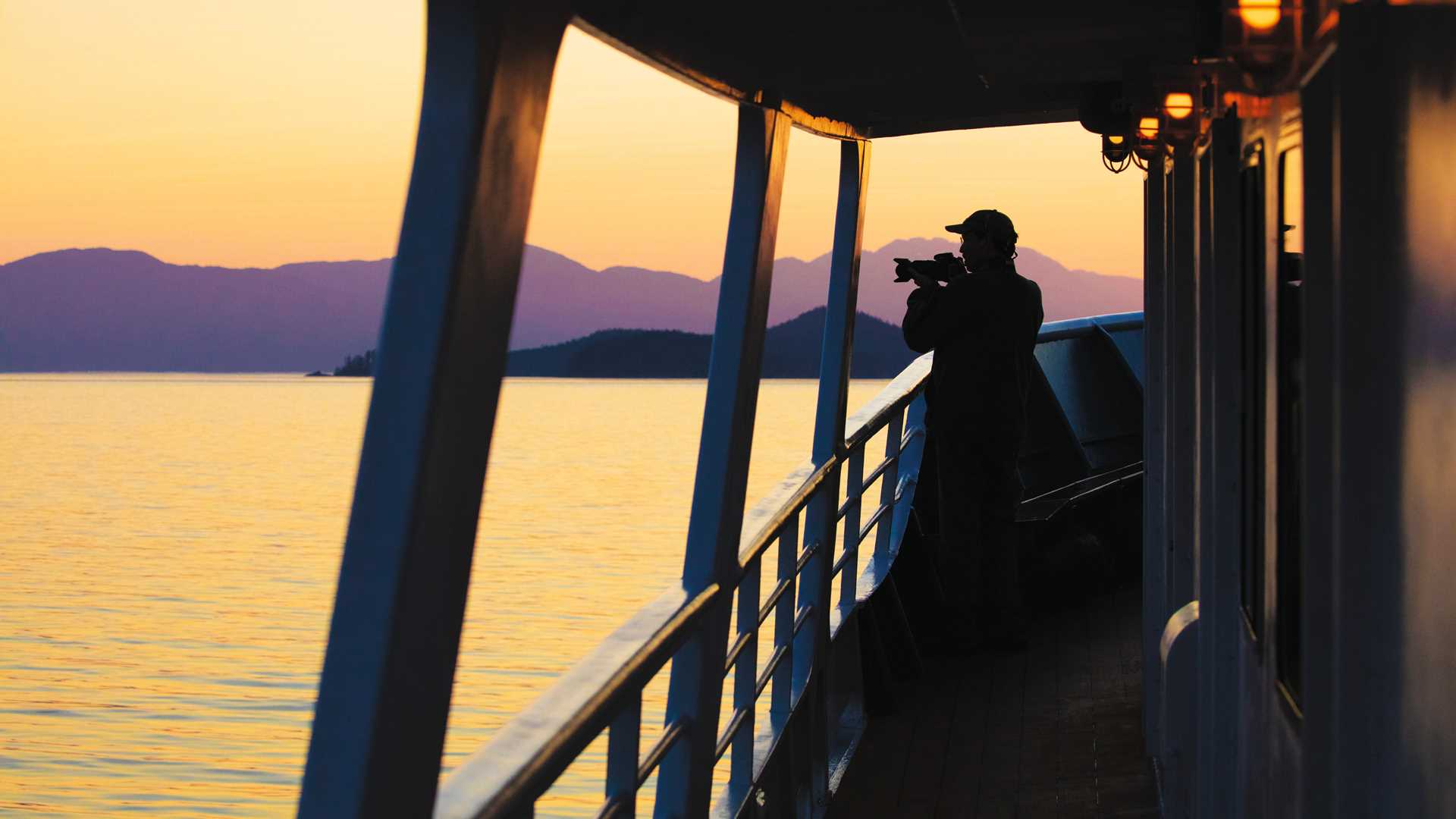 A man photographs the Alaskan landscape at sunset.