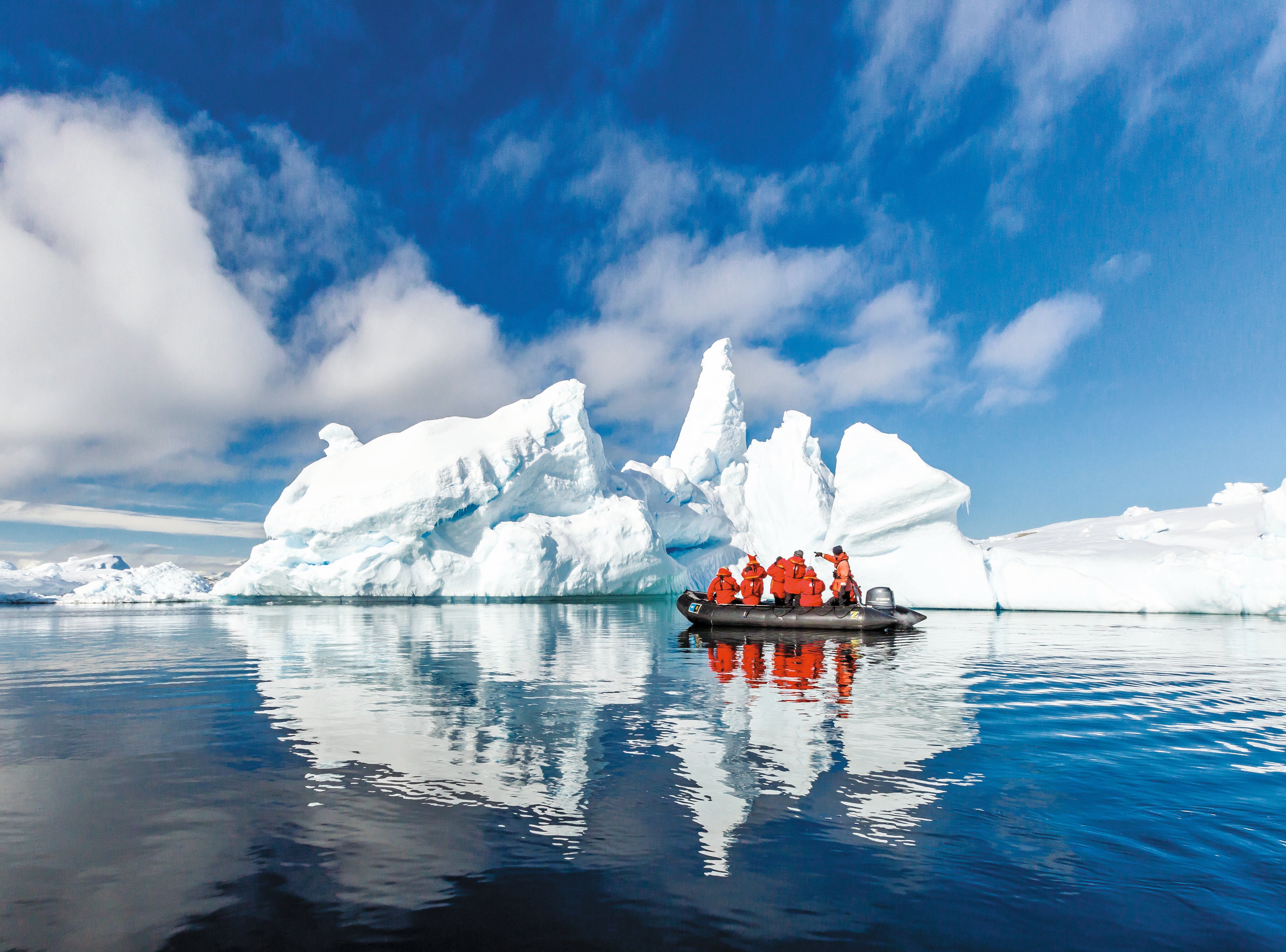 Guests cruise past large icebergs in a Zodiac.