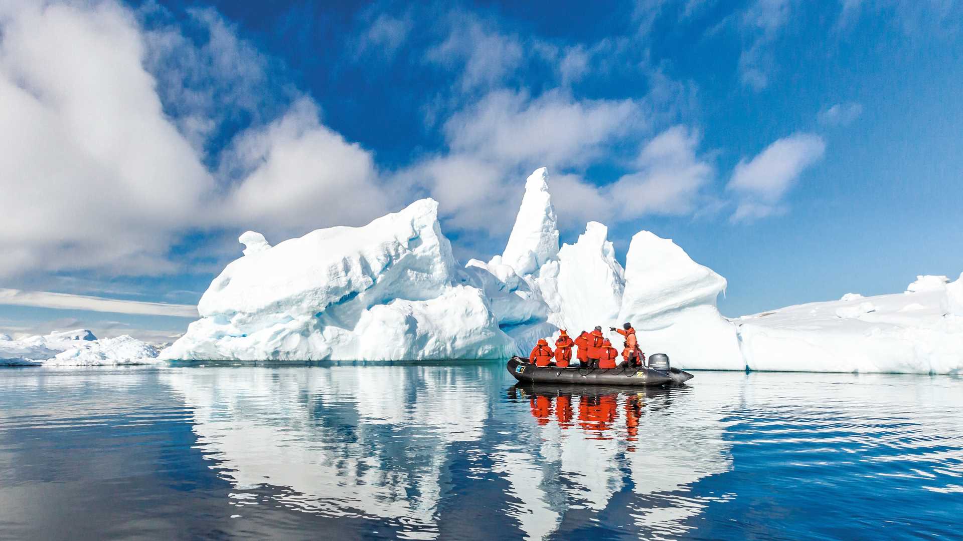 Guests cruise past large icebergs in a Zodiac.
