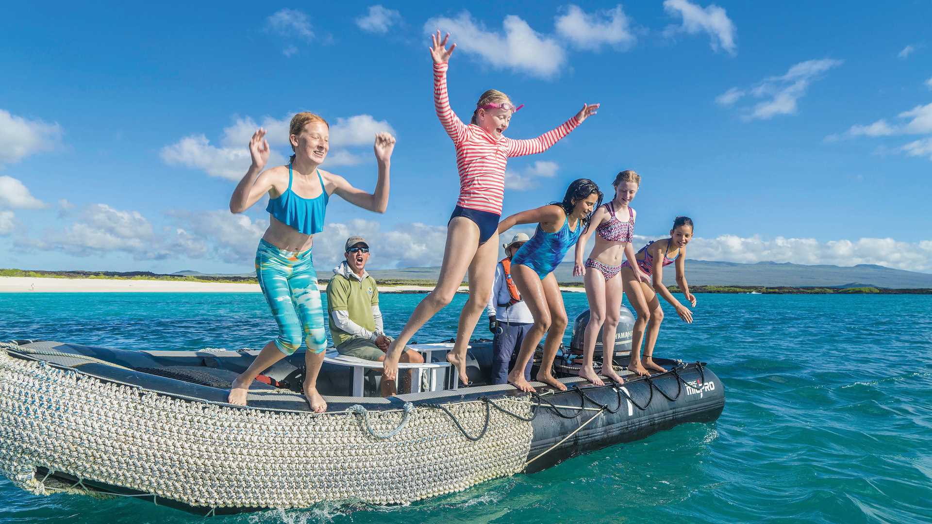 Kids jump into water off a Zodiac boat in Galápagos.
