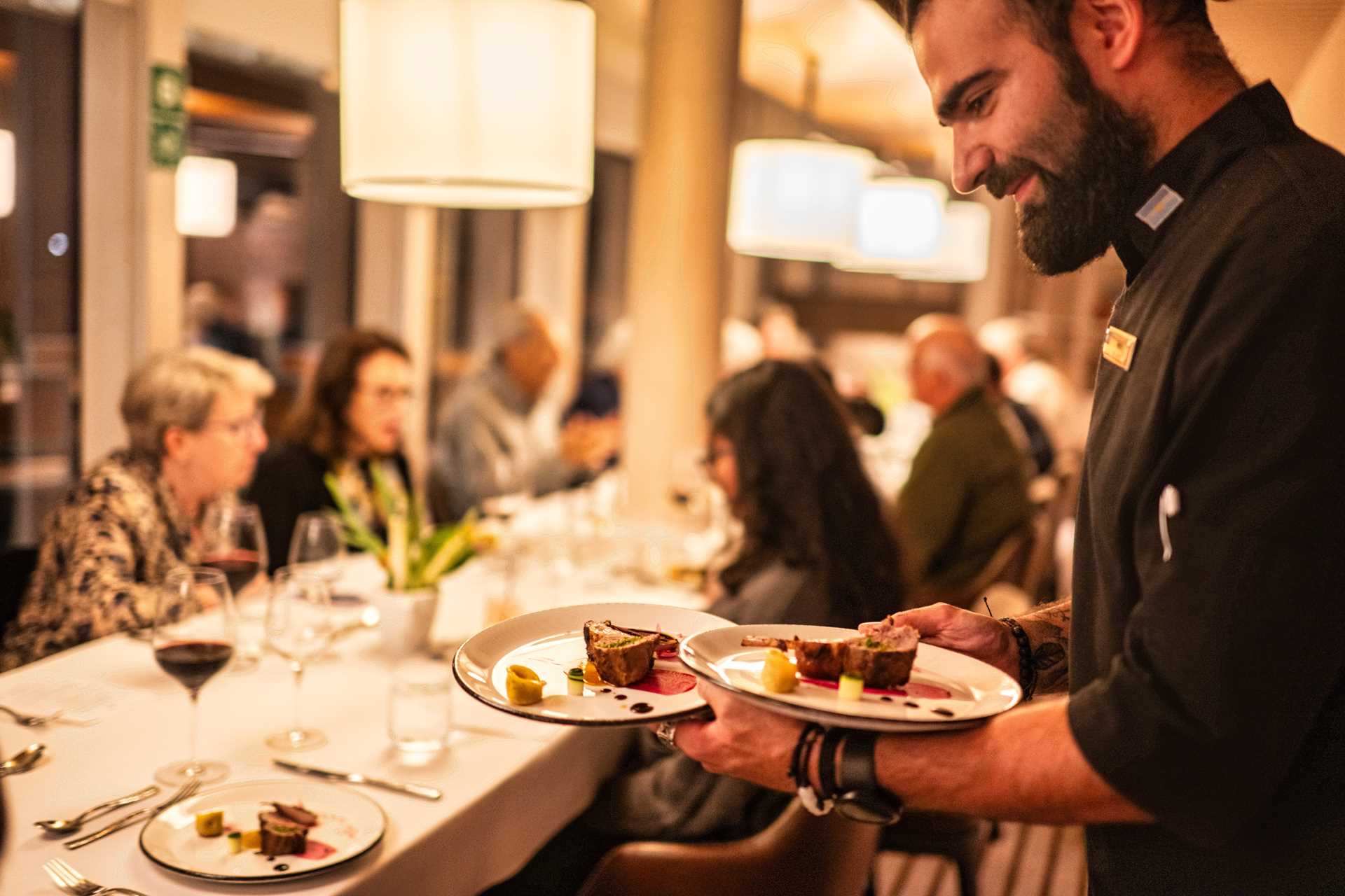 A waiter brings dishes to a table on the National Geographic Resolution.