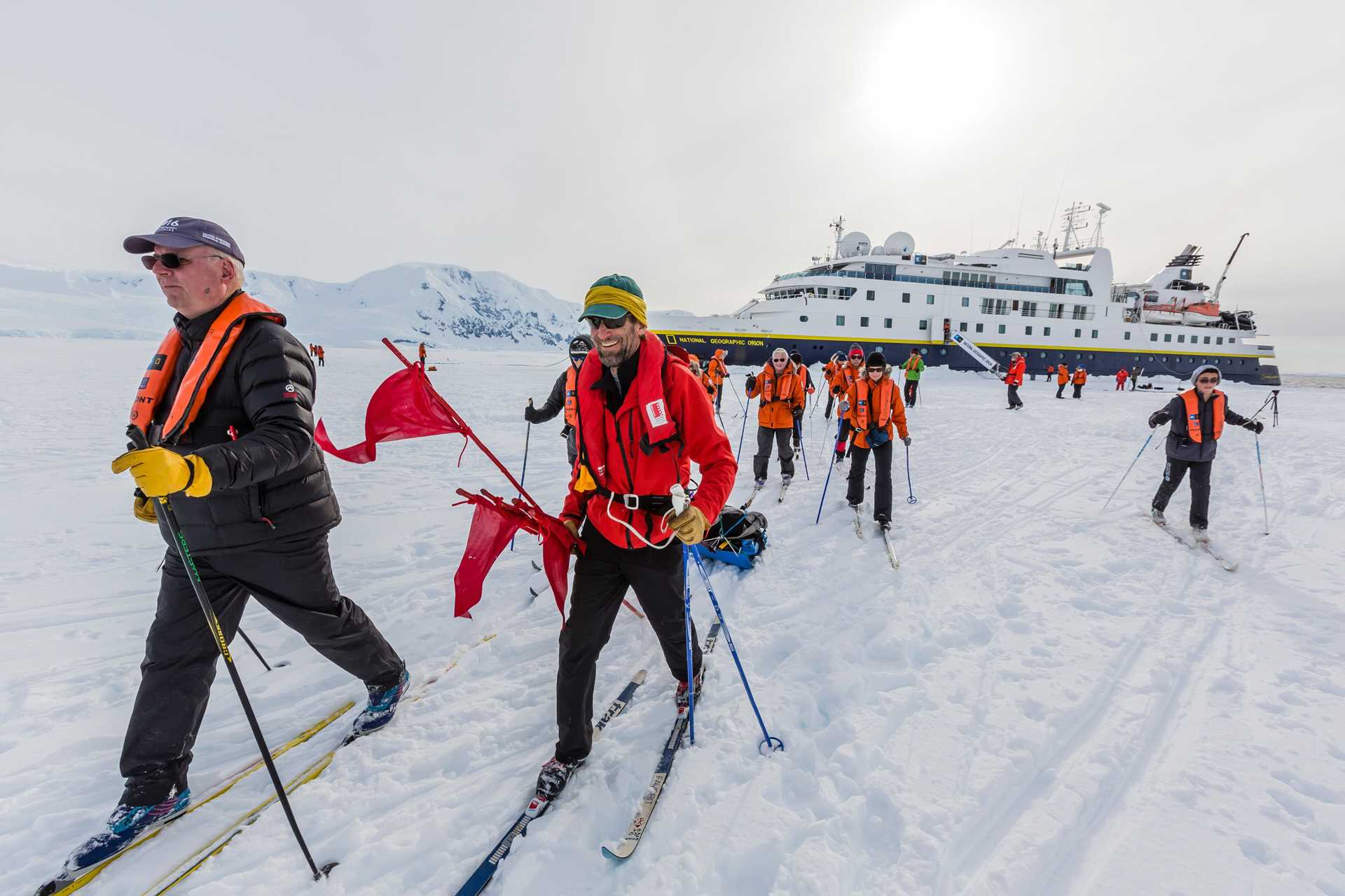 Guests cross-country ski on the pack ice in Cape Renaud with National Geographic Orion in the distance.