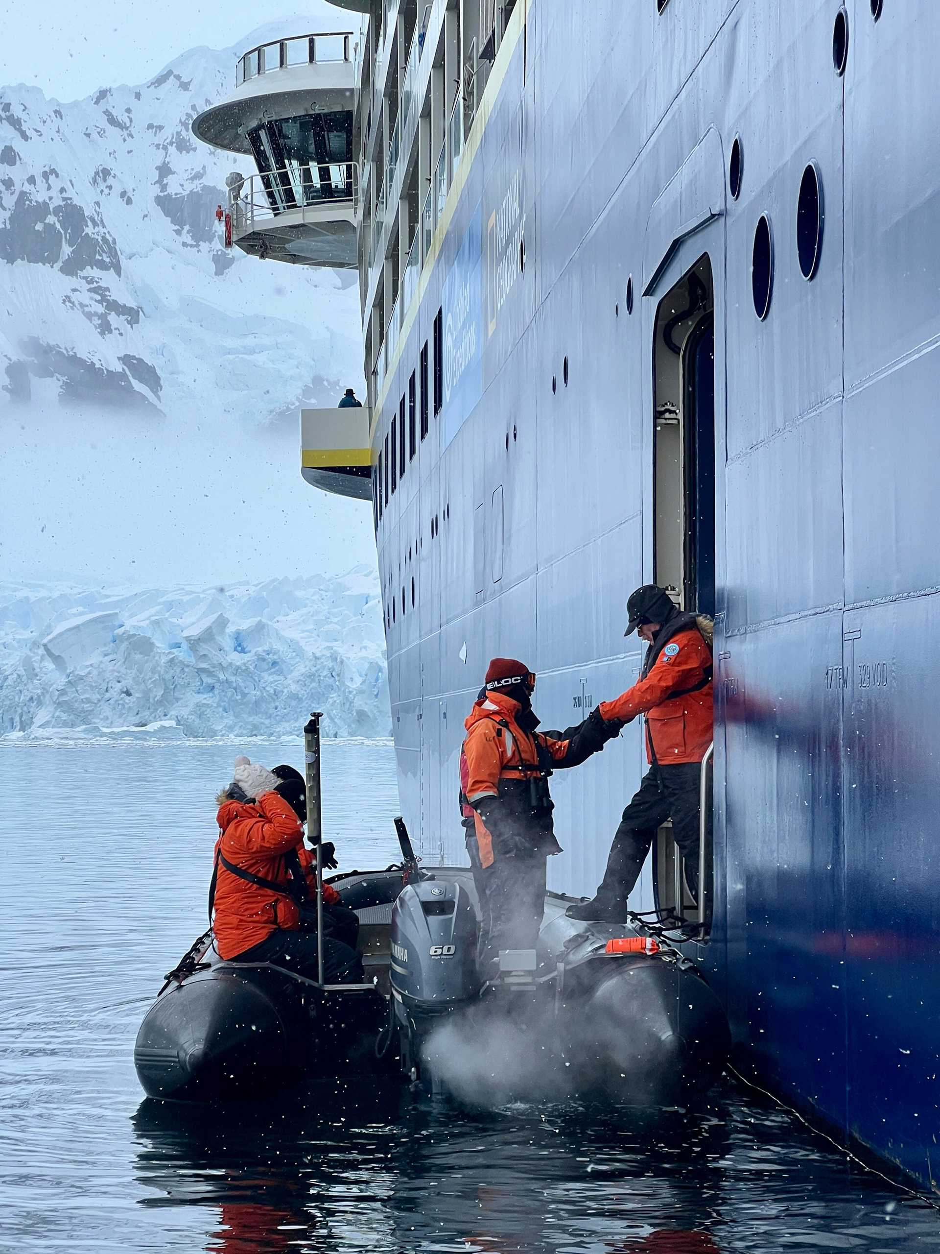 people embark a zodiac craft from the side of a ship