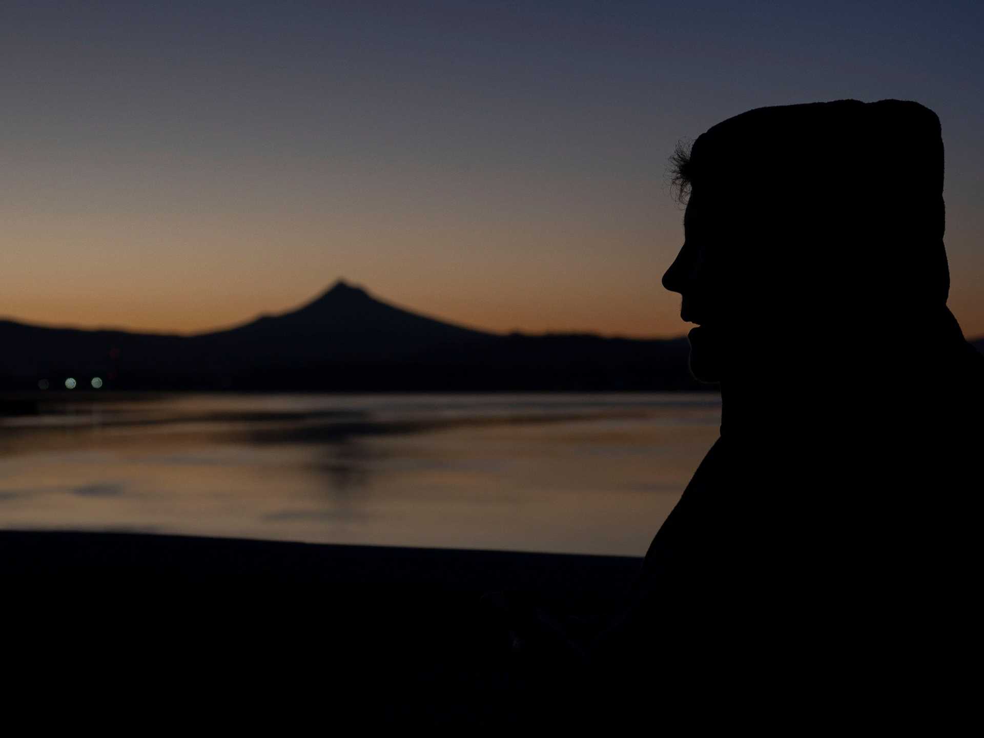 the silhouette of a man in front of a sunrise