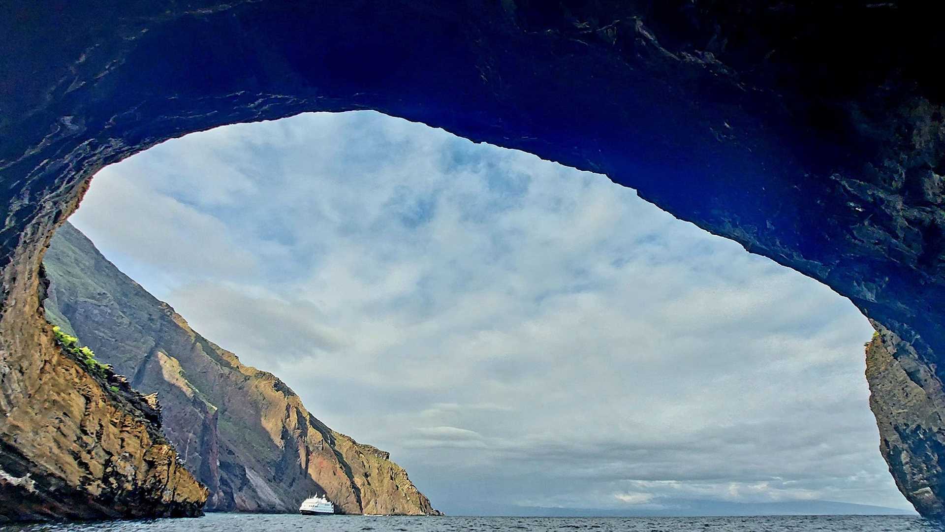 view of National Geographic Endeavour II from inside a large natural cave on the beach