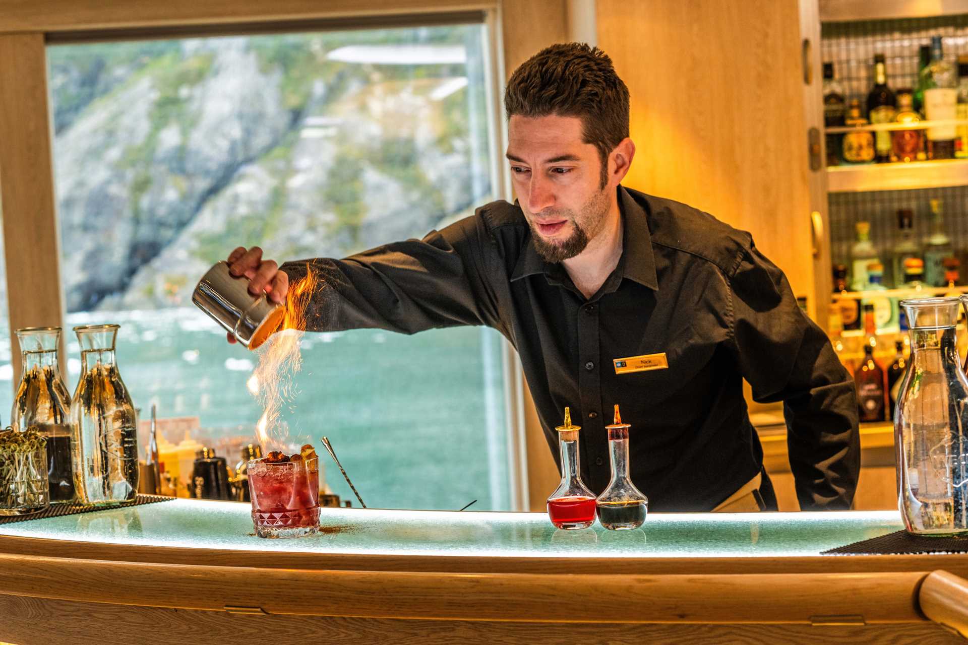 A bartender makes a flaming cocktail on the National Geographic Resolution