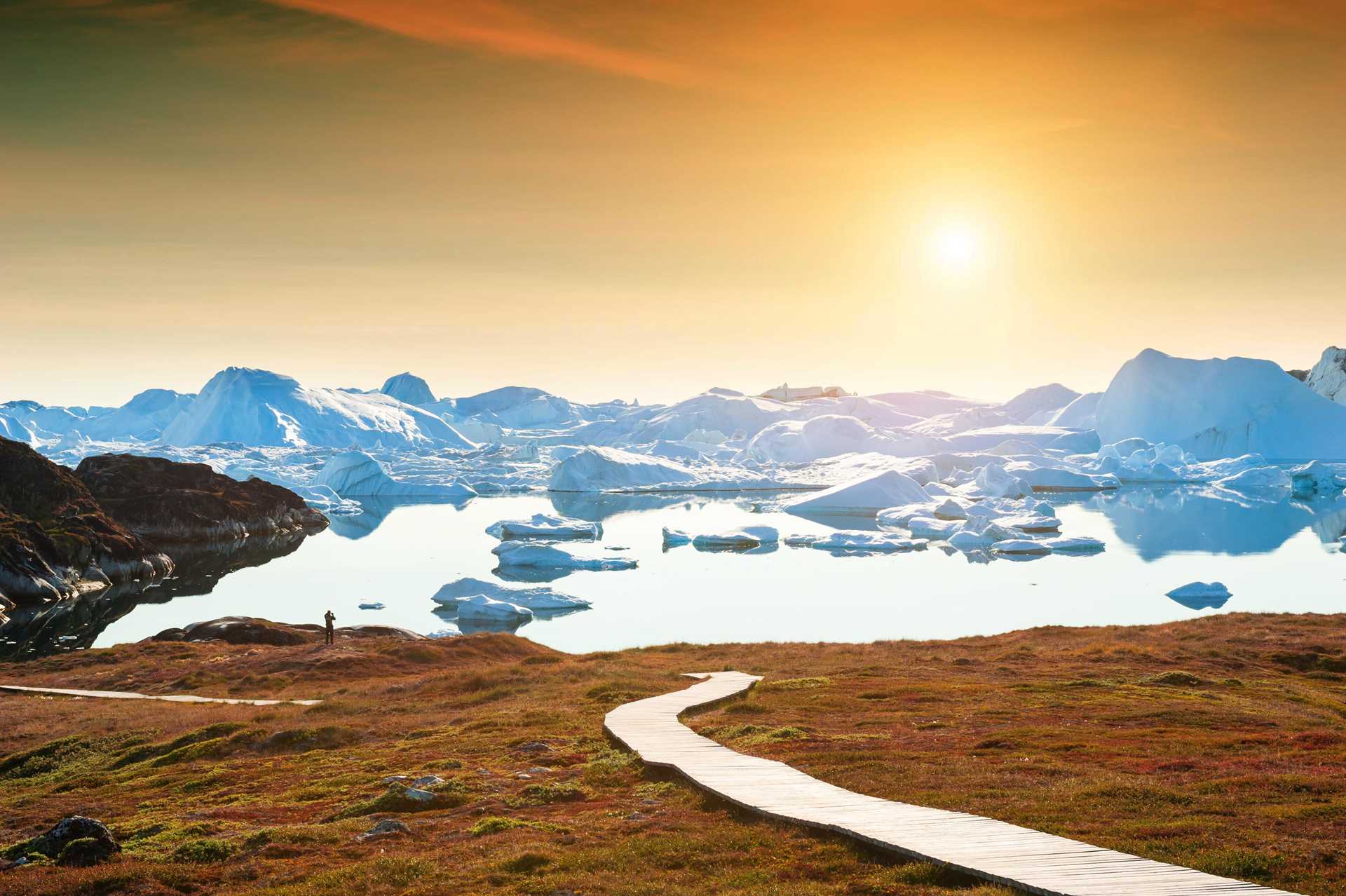 Hikers in Ilulissat, Greenland, walk in front of a glacier